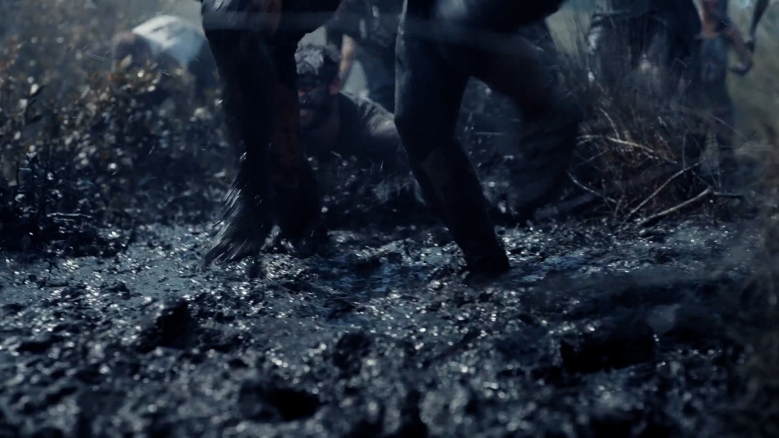 a group of people walking through a muddy field