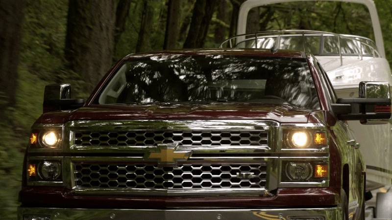 a truck driving down a road next to a forest