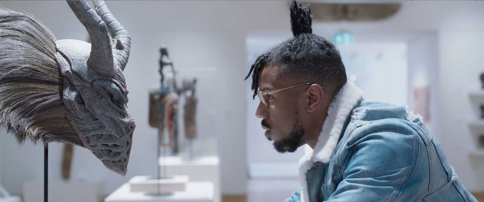 a man in a blue jacket looking at a sculpture