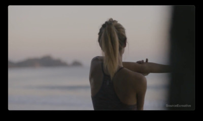 a woman standing on a beach with her back to the camera