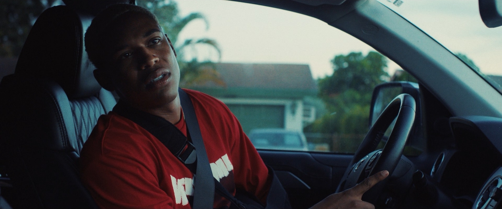 a man in a red shirt driving a car