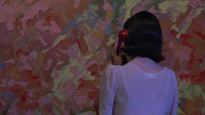 a woman standing in front of a colorful wall talking on a cell phone