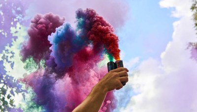 a person holding a colorful smoke bomb in their hand