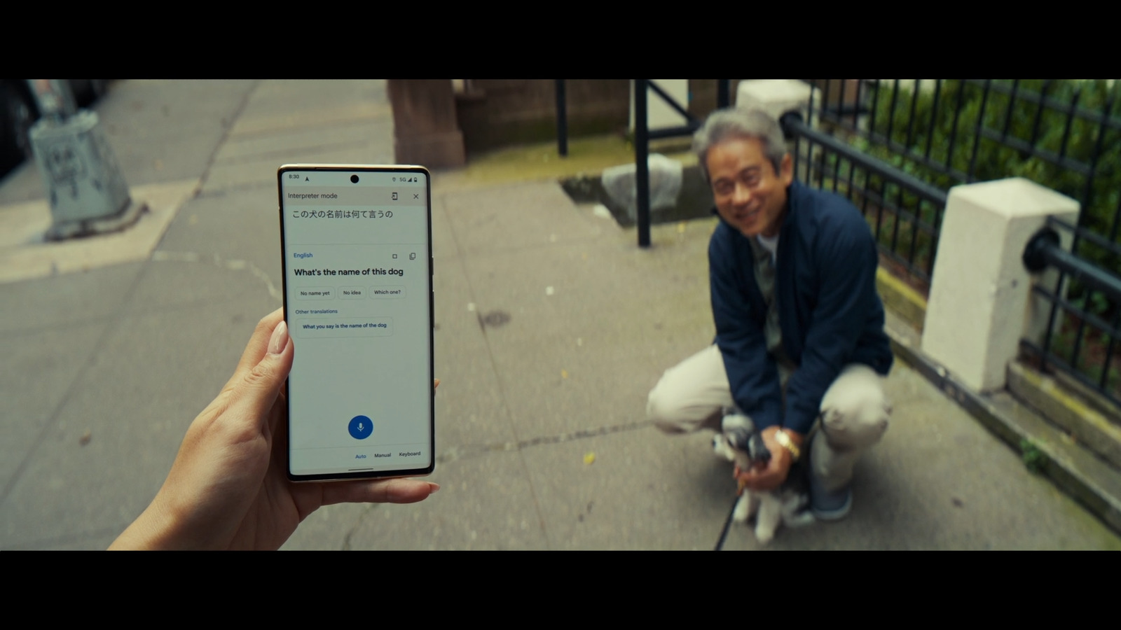 a man squatting down while holding a cell phone