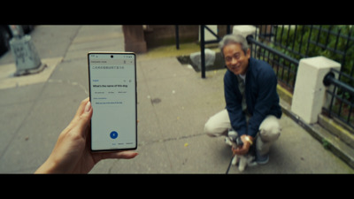 a man squatting down while holding a cell phone