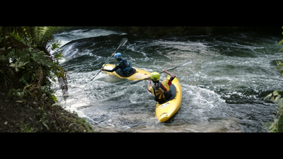 two people in kayaks paddling down a river