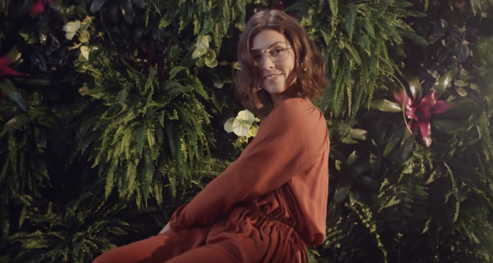 a woman in a red dress sitting in front of a green wall