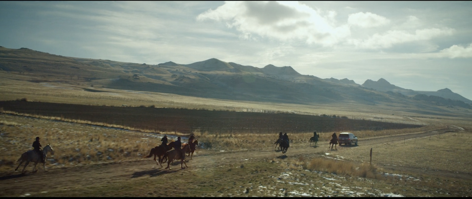 a group of people riding horses down a dirt road