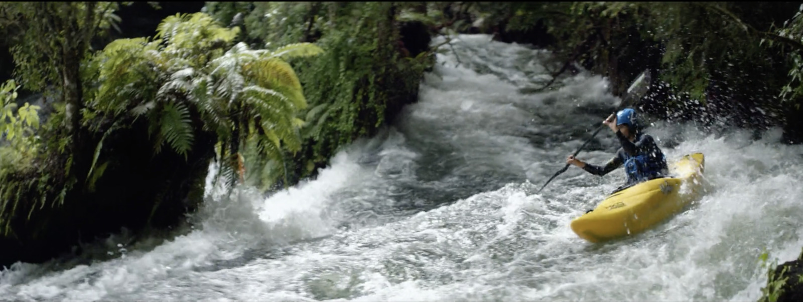 a man riding a yellow kayak down a river