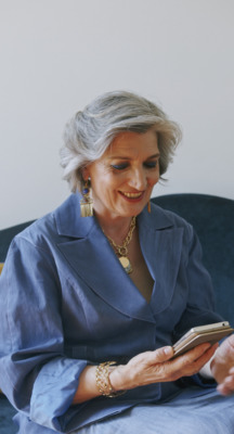 a woman sitting on a couch looking at a cell phone