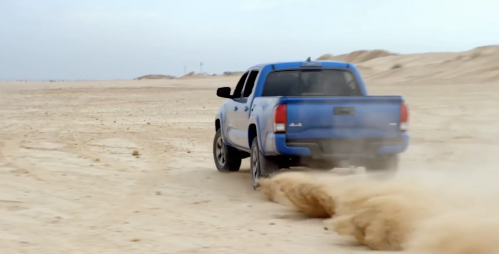 a blue pick up truck driving through a desert