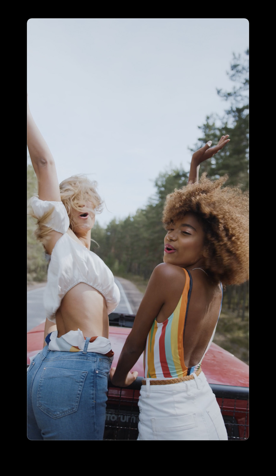 two women standing next to each other near a car