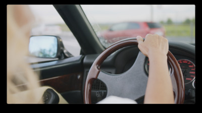 a woman driving a car with her hand on the steering wheel