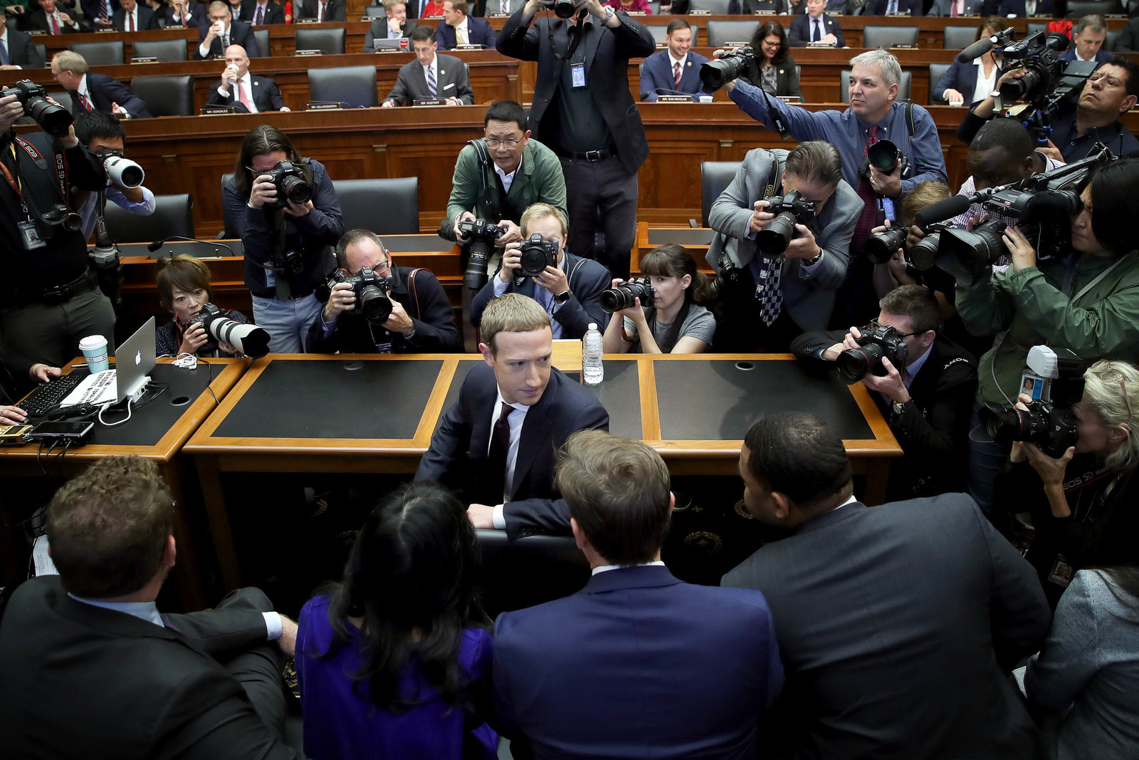 a man in a suit is surrounded by photographers