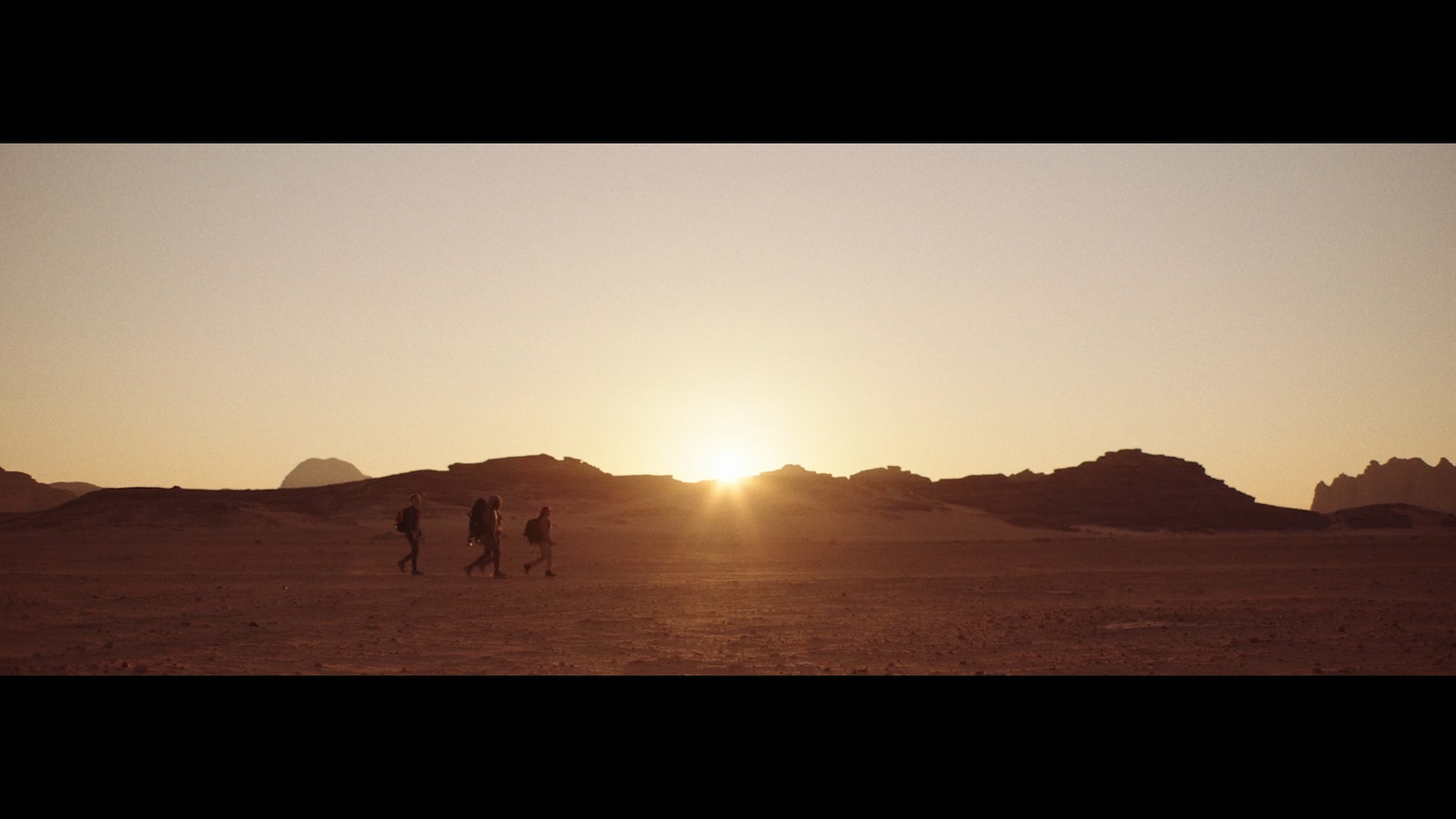 a group of people walking across a desert