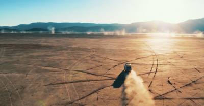 a car driving through a desert with a lot of dust