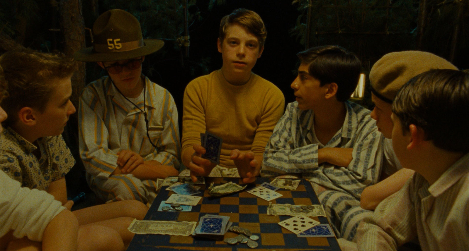 a group of young men sitting around a table playing cards