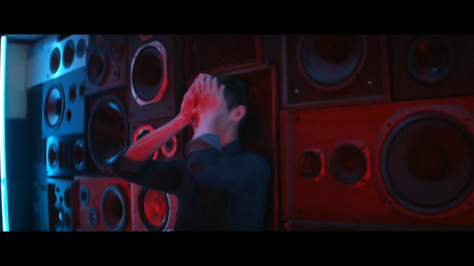 a man standing in front of a wall of speakers