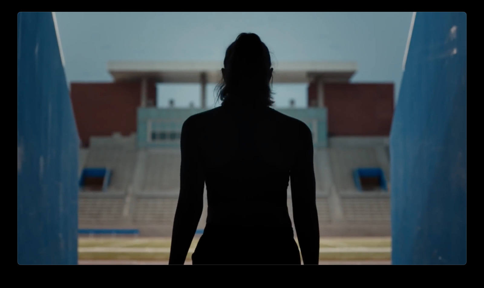 a silhouette of a woman standing in front of a stadium