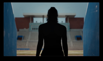 a silhouette of a woman standing in front of a stadium