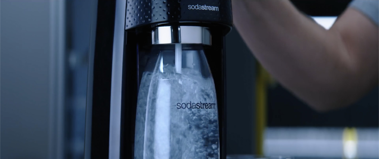 a person holding a water bottle near a water dispenser