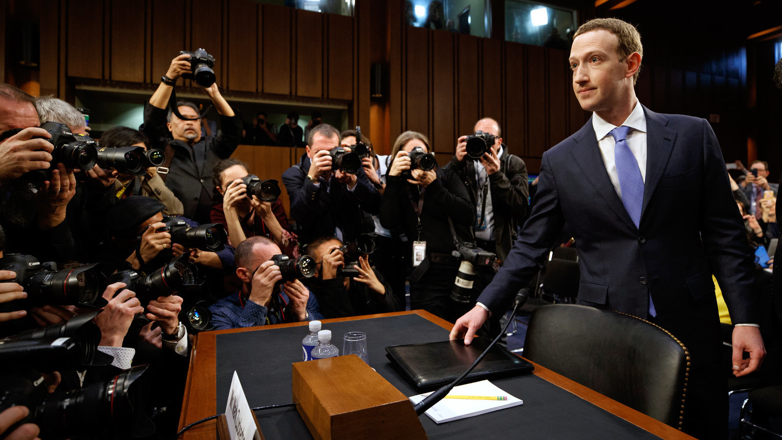 a man in a suit and tie standing in front of a table