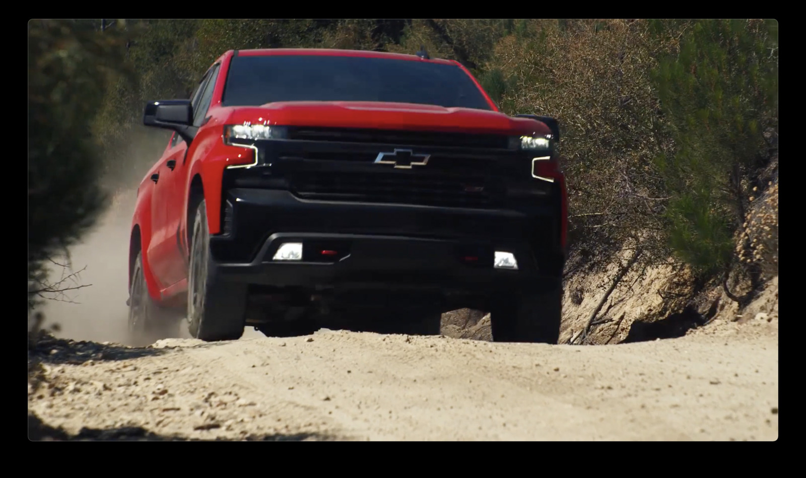 a red truck driving down a dirt road