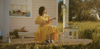 a woman sitting on a porch playing a guitar