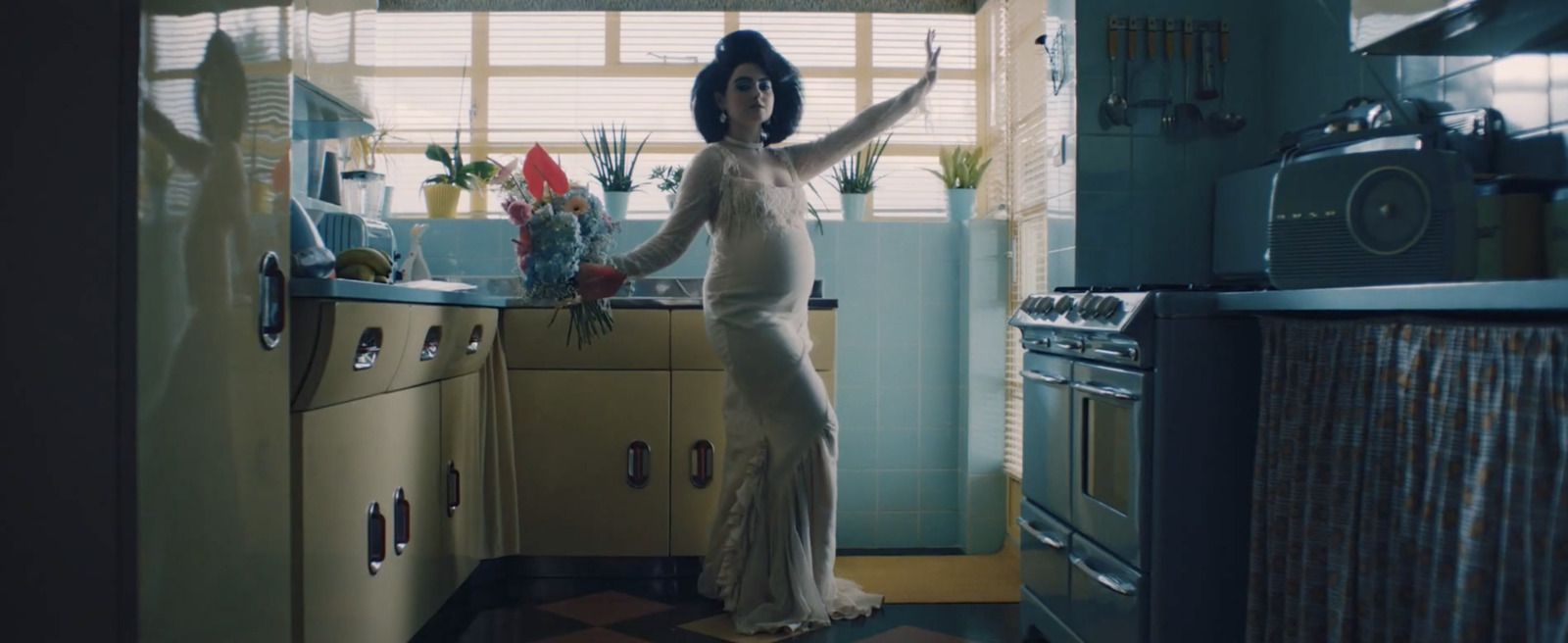 a woman standing in a kitchen holding a bouquet of flowers