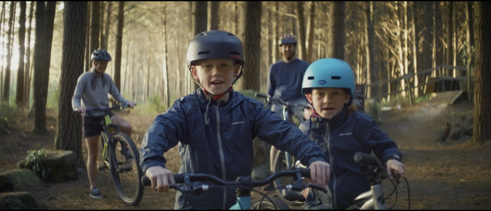 a couple of kids riding bikes through a forest