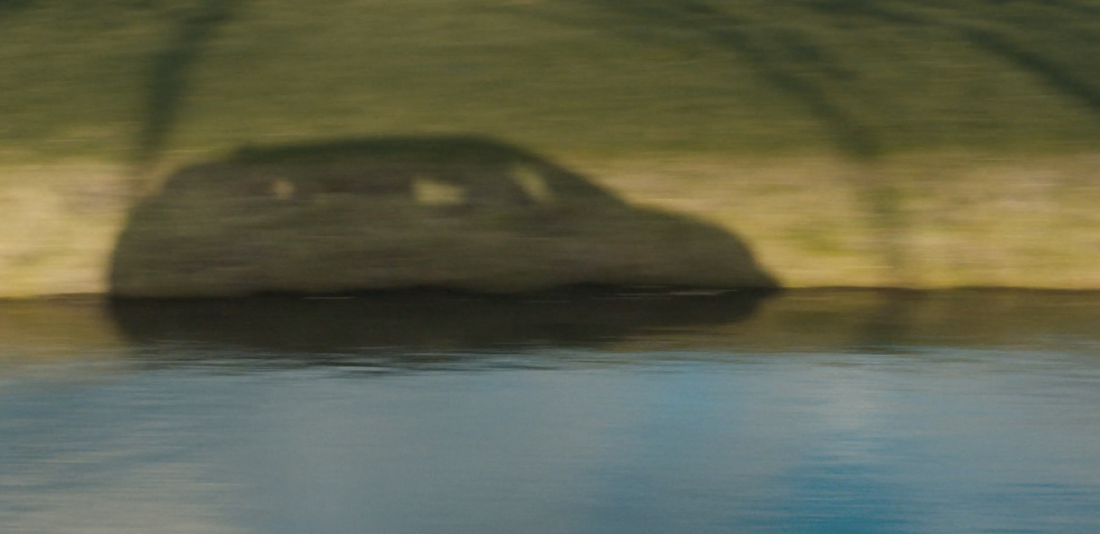 a blurry photo of a car parked on the side of a body of water