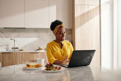 a woman sitting at a kitchen table using a laptop