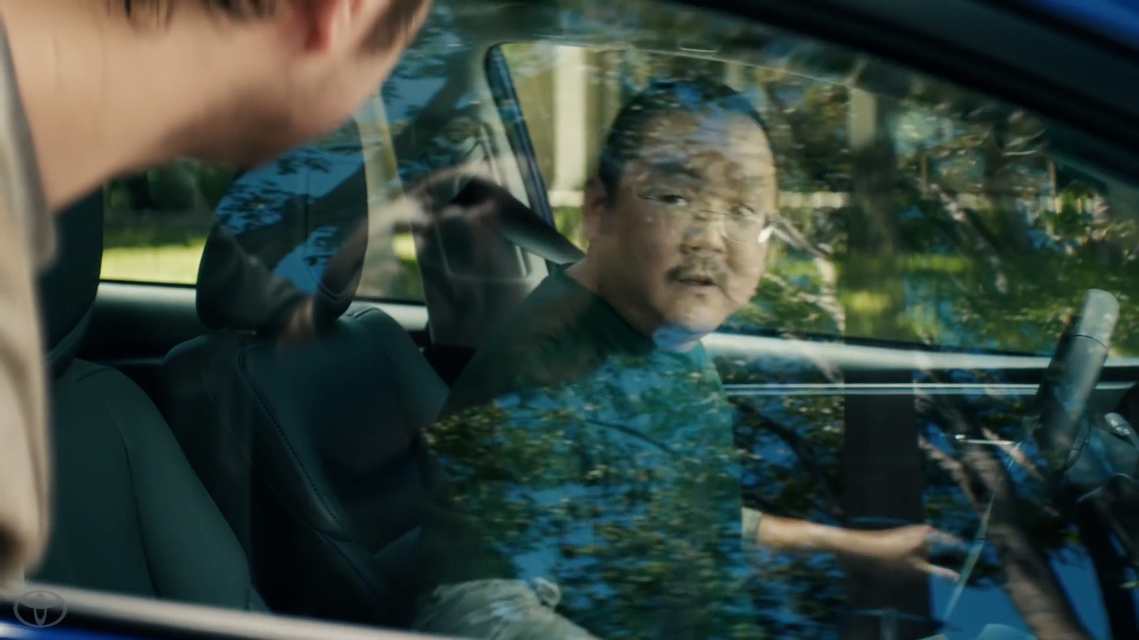 a man sitting in a car with his hand on the steering wheel