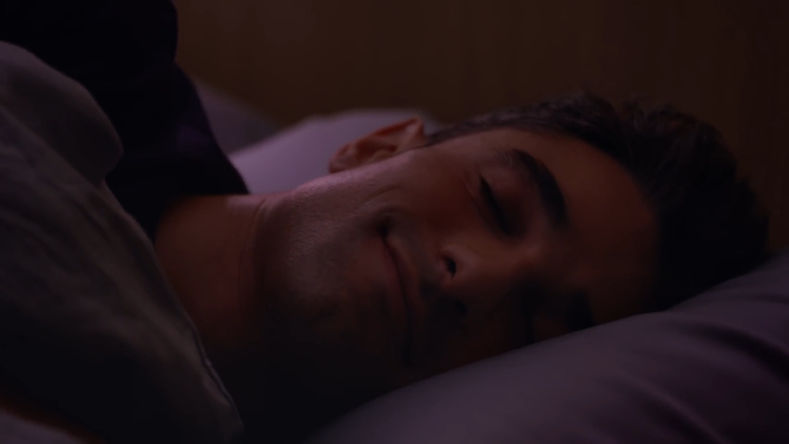 a man laying in bed with his eyes closed