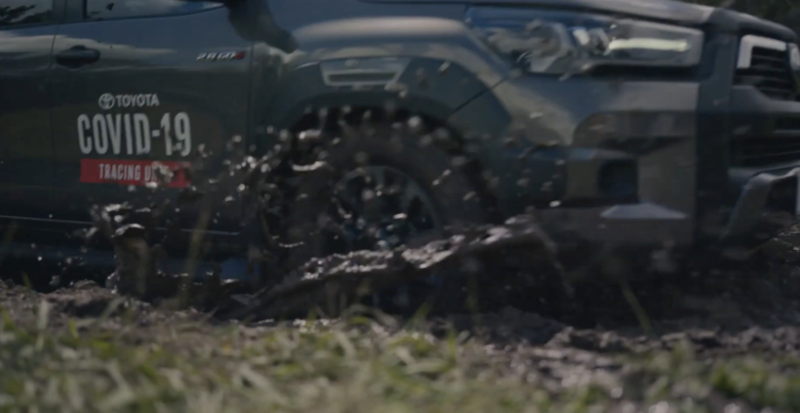 a black truck driving through a muddy field