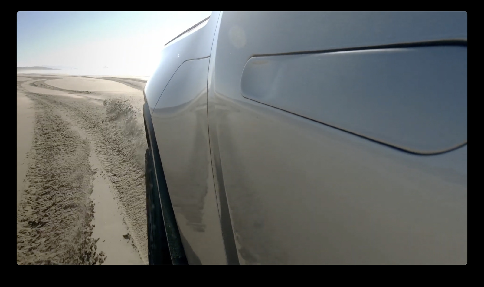 a white car driving down a sandy road