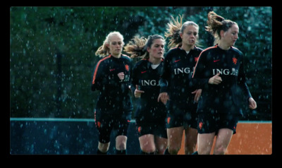 a group of women's soccer players running in the rain