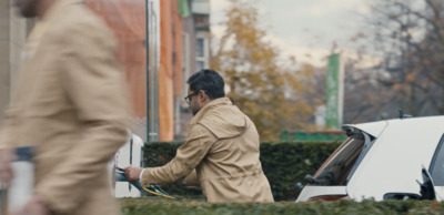 a man in a trench coat is pumping gas into a car