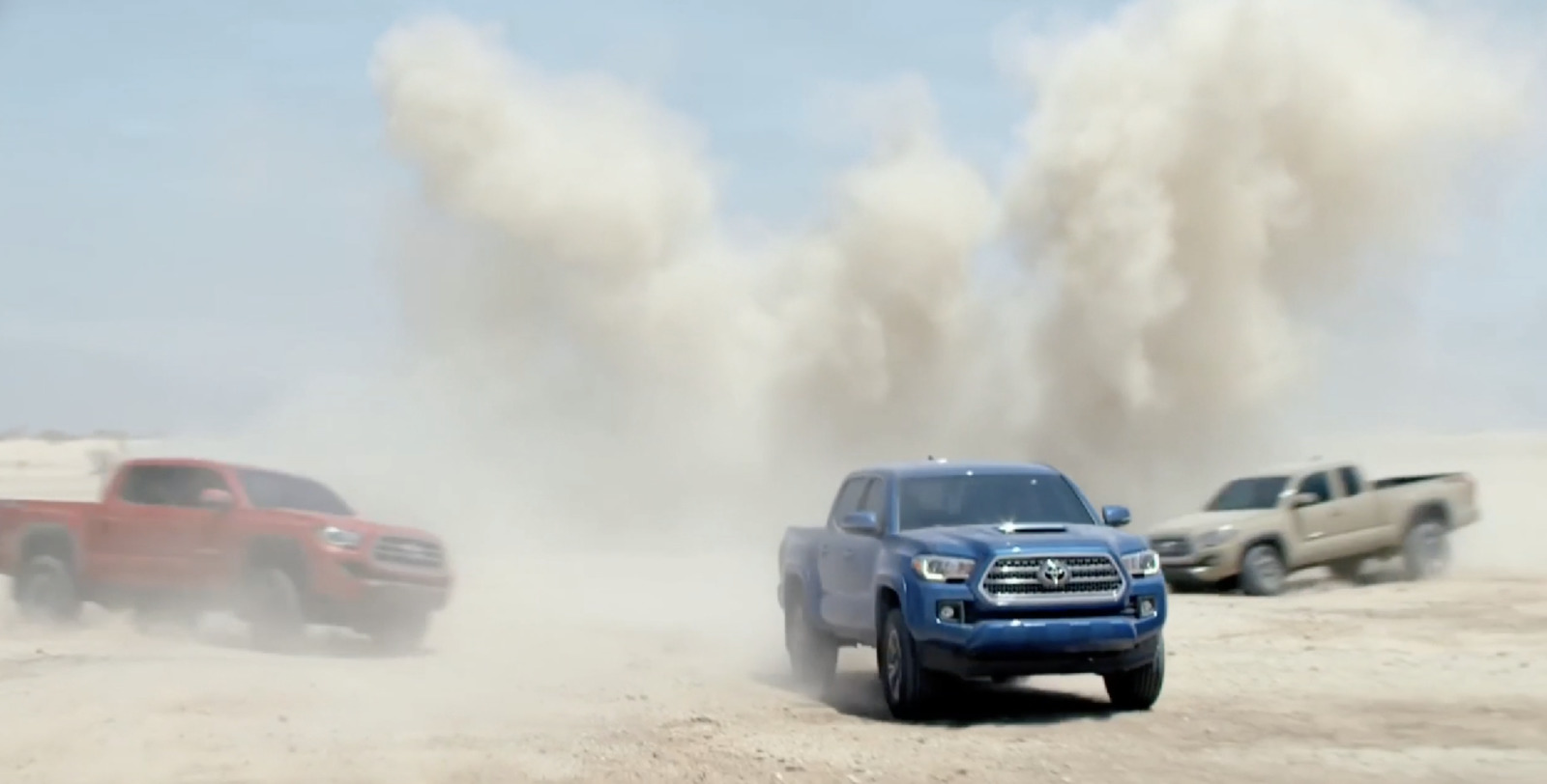 a group of trucks driving down a dirt road