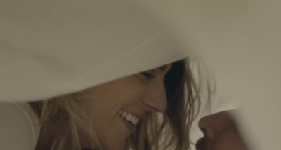 a close up of a smiling woman peeking out from behind a sheet