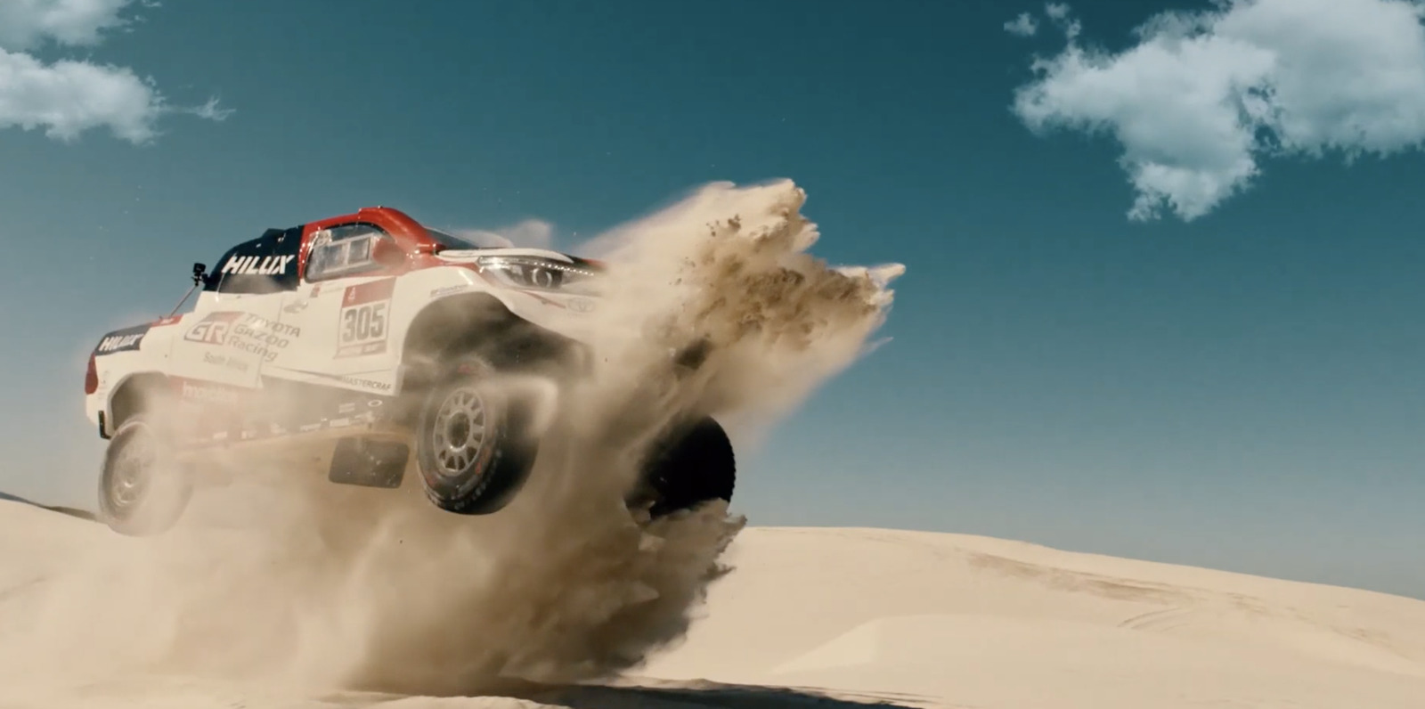 a white truck driving through the sand dunes