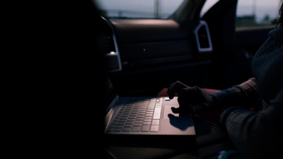 a person sitting in a car using a laptop computer