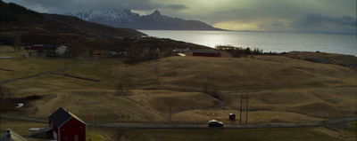 a hill with a house on top of it next to a body of water