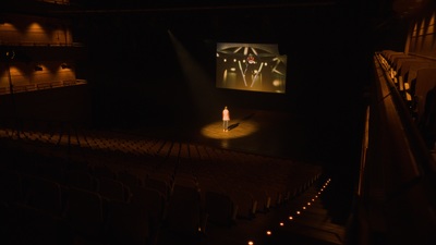 a person standing on a stage in front of a screen