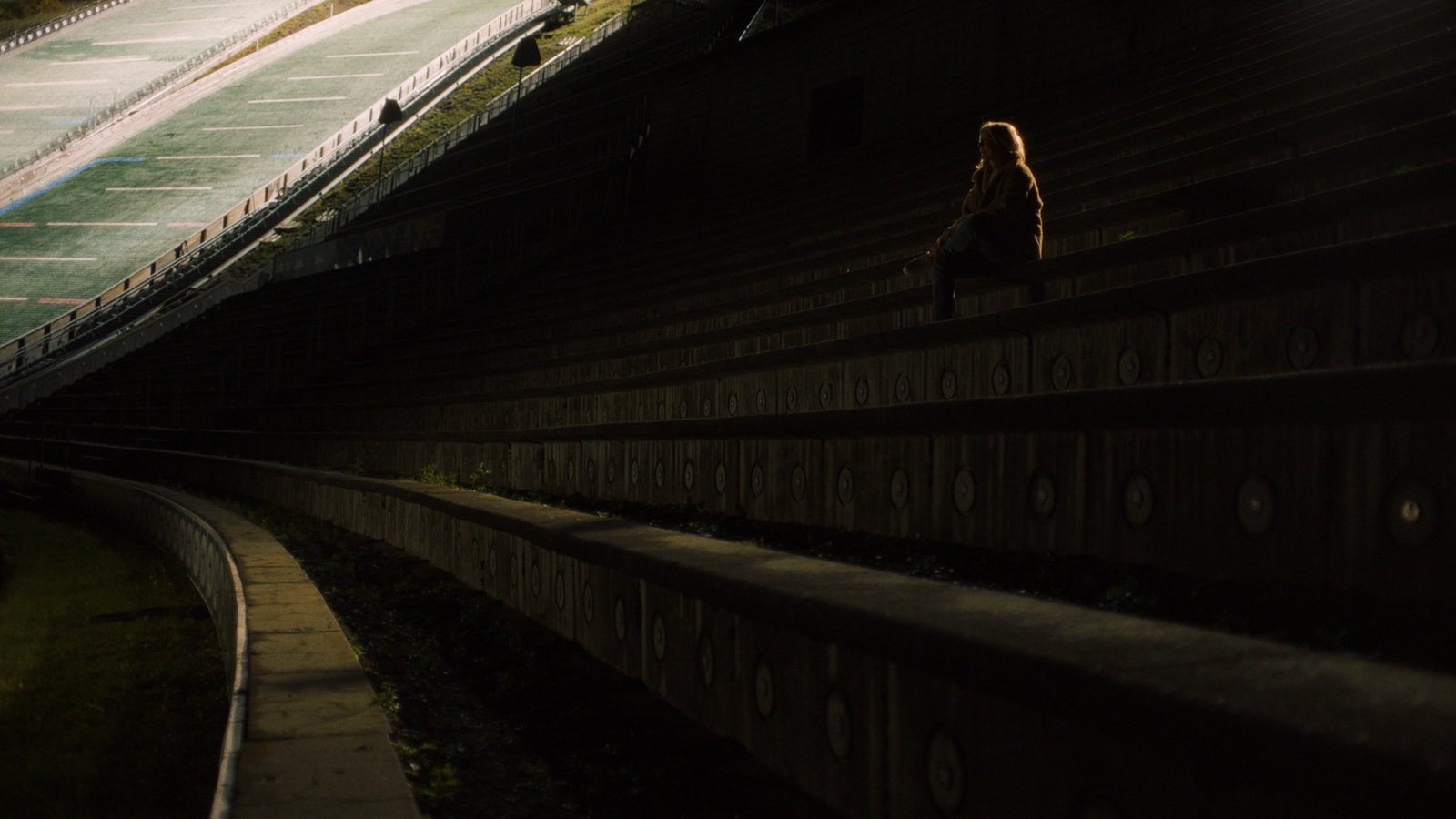 a woman sitting on a bench in a stadium