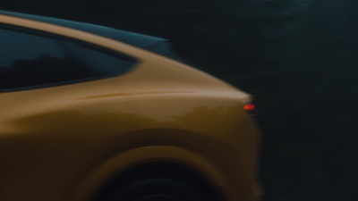 a yellow car driving down a street next to a forest