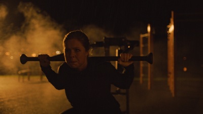 a woman holding a baseball bat on a street