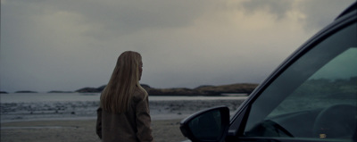 a woman standing next to a car on a beach