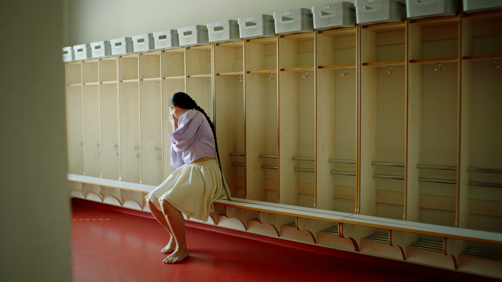 a woman leaning against a wall in a locker room