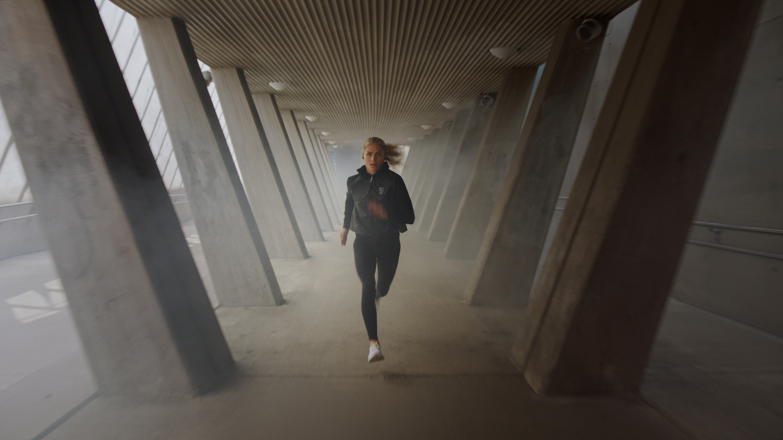 a woman running down a hallway in a building